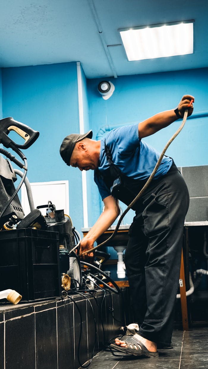 Mastering the First Impression: Your intriguing post title goes here A technician in blue attire repairing equipment in an indoor workshop setting.